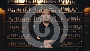 Portrait of an adult male restaurateur against the background of the wine shelves of an expensive restaurant. The