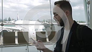 Portrait of adult man, who is using his smartphone in the airport.