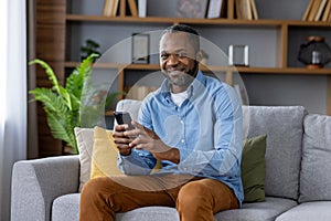 Portrait of adult mature man, African American man smiling and looking at camera with phone in hand, happy sitting on