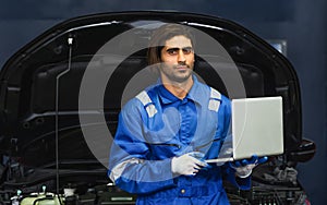 Portrait Adult Professional handsome caucasian male mechanic wearing uniform, holding laptop for fix, repair, check, inspect car