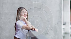 Portrait of an adult Thai student girl in university student uniform. Asian beautiful girl sitting smiling happily at university