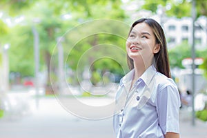 Portrait of adult Thai student in university student uniform. Asian beautiful girl standing smiling confidence at outdoors