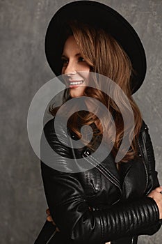 Portrait of an adult woman with bright makeup and perfect skin in a black trendy hat and leather jacket