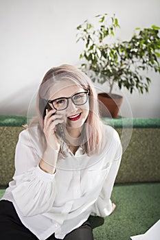 Portrait of an adult woman entrepreneur with grayish hair in a managerial position, dressed in a white blouse and busy working in