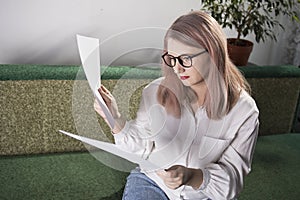 Portrait of an adult woman entrepreneur with grayish hair in a managerial position, dressed in a white blouse and busy working in