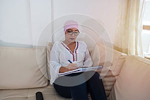 Portrait of an adult woman filling out a patient form at the doctor`s office during her recovery from cancer