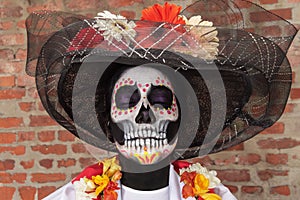 Portrait of an adult woman with her eyes closed wearing La Calavera Catrina make-up and costume