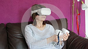 Portrait of an adult woman in virtual reality glasses VR helmet holds controllers in her hands plays a game while