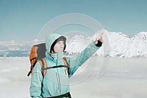 Portrait of adventurous young man on winter mountain top view pointing out.