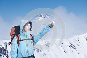 Portrait of adventurous young man on winter mountain top view pointing out.