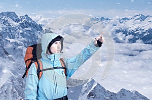 Portrait of adventurous young man on winter mountain top view pointing out.