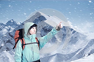 Portrait of adventurous young man on winter mountain top view pointing out.