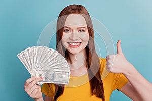 Portrait of adviser positive lady hold fan dollars raise thumb up on blue background