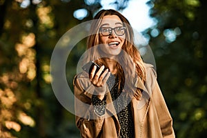 Portrait of affable woman using cell phone while walking through empty boulevard