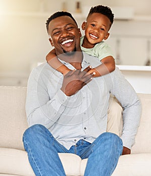 Portrait of an affectionate black man holding his child on a couch. African american father bonding with his son at home