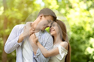 Portrait of affectionate couple hugging at park on sunny summer day