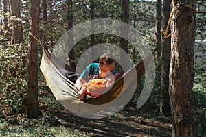 Portrait of an affectionate young couple lying on a hammock kissing. Romantic young man and woman on hammock in the wilderness