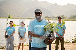 Portrait of afirican man with background Group of volunteer holding Pot With Green Plant Smiling To Camera Standing On river.