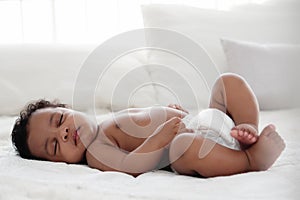Portrait of african american baby girl sleeping on white bed