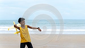 Portrait of African American boys play flying plane at beach