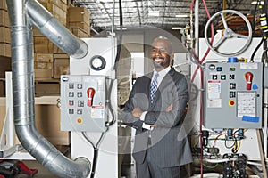 Portrait of African American businessman standing arms crossed with machinery in background