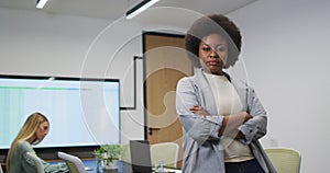 Portrait of african american businesswoman smiling in office, with colleague working in background