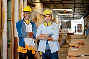 Portrait of African American and Caucasian carpenter man stand with arm crossed and look at camera in wood factory workplace