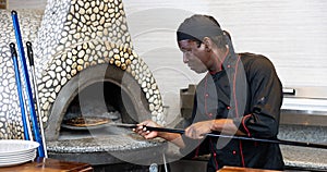 Portrait of african american chef man baking pizza in oven