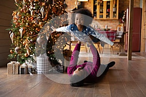 Portrait African American father carrying daughter, celebrating Christmas at home