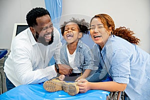 Portrait of African American father laugh with little girl and Asian wife and stay in area of emergency room and they look