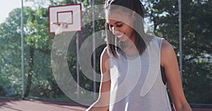 Portrait of african american female basketball player holding ball on sunny court, in slow motion