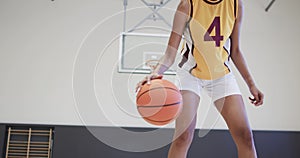 Portrait of african american female basketball player training in indoor court, in slow motion