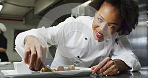 Portrait of african american female chef garnishing dish looking at camera and similing