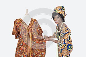 Portrait of an African American female fashion designer working on dashiki over gray background