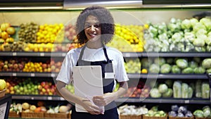 Portrait of African American female staff person standing with tablet in supermarket and smiling