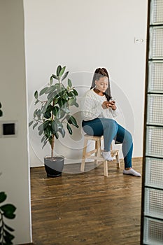 Portrait of African American female student dressed casually holding mobile phone and typing messages and communicating