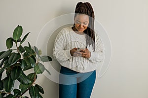 Portrait of African American female student dressed casually holding mobile phone and typing messages and communicating