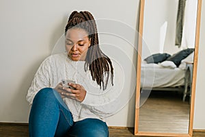 Portrait of African American female student dressed casually holding mobile phone and typing messages and communicating
