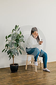 Portrait of African American female student dressed casually holding mobile phone and typing messages and communicating