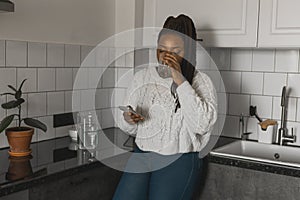 Portrait of African American female student dressed casually holding mobile phone and typing messages and communicating