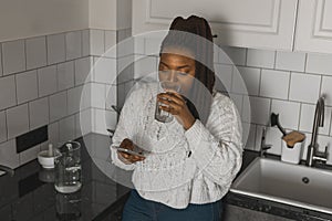 Portrait of African American female student dressed casually holding mobile phone and typing messages and communicating