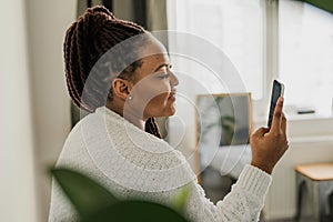 Portrait of African American female student dressed casually holding mobile phone and typing messages and communicating