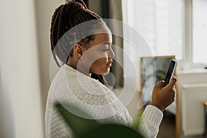 Portrait of African American female student dressed casually holding mobile phone and typing messages and communicating