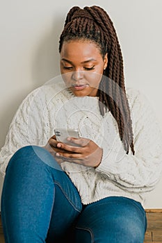 Portrait of African American female student dressed casually holding mobile phone and typing messages and communicating