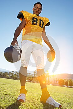 Portrait of african american Football Player Holding Helmet and Ball in field