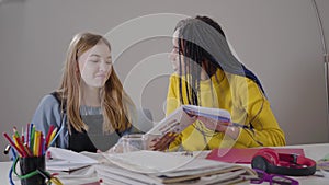 Portrait of African American girl making victory gesture and giving high five to Caucasian friend. Teens studying