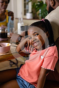 Portrait of african american girl smiling at camera while having breakfast with parents at table