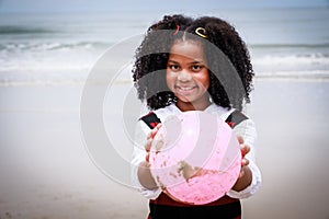 Portrait of African American girl smiling and holding a pink ball on the beach. Happy vacation holiday. Relaxation in vacation in