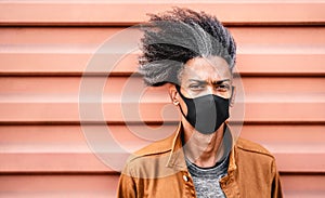 Portrait of african american guy wearing black protective face mask - New normal lifestyle concept with young man