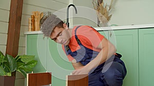Portrait of African American handyman assembling DIY bedside table with hammer